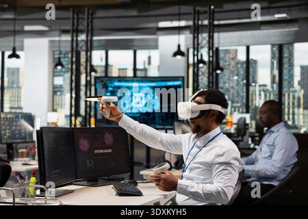 IT specialist in office fighting hacker ddos attack using virtual reality technology to find malware in servers. Startup programmer using VR headset equipment to do software debugging, fixing virus Stock Photo