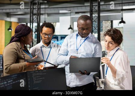 Engineering team in artificial intelligence tech company workplace conducts code reviews. Teamworking colleagues using application in office to design and implement machine learning algorithms Stock Photo