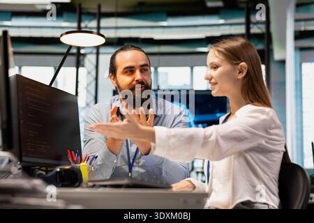 Lead engineer providing support to new programmer in software development agency. Seasoned developer explaining best practices to trainee during internship in tech startup company Stock Photo