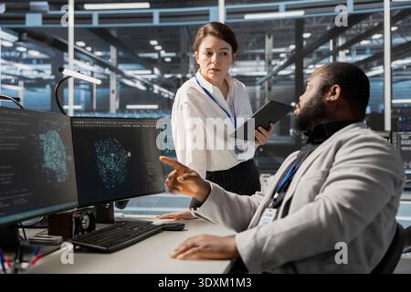 Data center software developers use AI visualization tool to optimize resource allocation. Server hub engineering team uses artificial intelligence analysis on computer to do maintenance Stock Photo