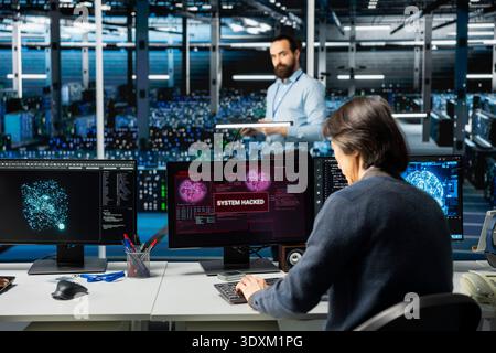 Engineers in AI server farm alerted by hacking incident involving theft of sensitive data. Teamworking data center IT specialists alarmed by computer virus triggered by security systems Stock Photo