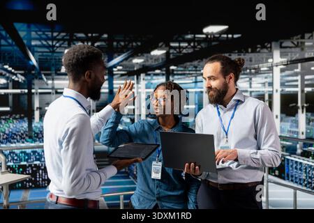 Team leader and workers celebrating IT progress with high five, enjoying software management achievement and cheering for success. Confident engineering team clapping hands on industrial platform. Stock Photo