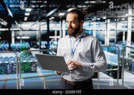 Software developer reviews data management for server rigs with tablet, handling AI processing tasks on industrial platform. Worker managing machine learning technology for development. Stock Photo
