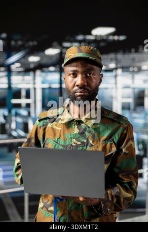 Black military IT expert in server hub using AI tools to oversee battlefield surveillance to develop warfare tactics. Army data center admin doing transmission analysis and live monitoring. Stock Photo