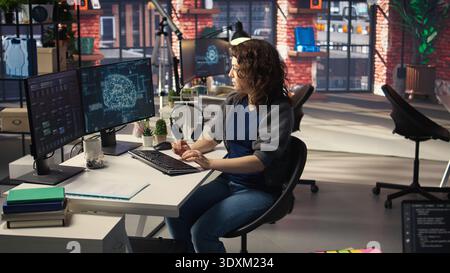 IT expert writing code and debugging on artificial intelligence neural networks computerized brain model. Woman tech support doing checkup on AI systems, cloud computing. Camera A. Stock Photo