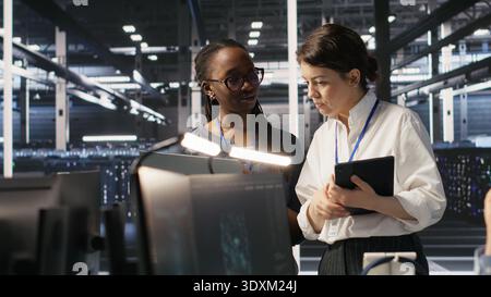Software developers working together in server farm, reviewing neural network code and LLM visualization dashboards. Teamworking data center colleagues monitoring AI system performance, camera A Stock Photo