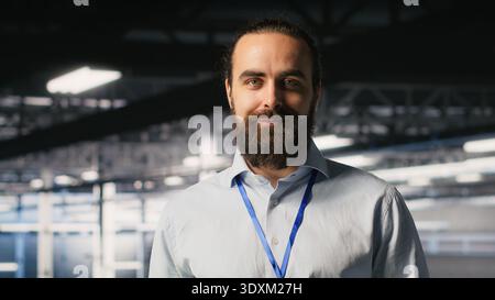 Cheerful data center admin doing maintenance tasks on tablet, ensuring optimal performance. Upbeat IT professional reviewing diagnostics and applying patches to server hub gear Stock Photo