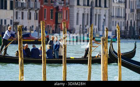 Traghetto gondola ferries commuters across Canal Grande, wooden mooring poles, Venice, Italy Stock Photo