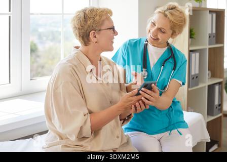 Nurse explaining to happy senior patient how to use health mobile app easy Stock Photo