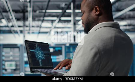 Software developer in data center uses AI technology on laptop to optimize storage volumes. IT expert in server hub facility using artificial intelligence to ensure seamless operations, camera B Stock Photo