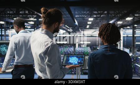 Data center engineering team doing maintenance on servers used for artificial intelligence processing. IT experts manage data center arrays used for machine learning training with tablet, Stock Photo