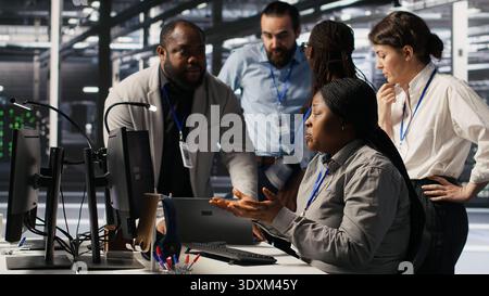 Angry technicians in server room fighting each other after encountering critical error popup during maintenance. Engineers having tense conversation, doing system recovery brainstorming chat, camera A Stock Photo