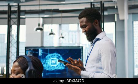 Joyous technician in office automating repetitive tasks using AI scripts. Upbeat man in workplace using artificial intelligence to speed up feature implementation, camera A Stock Photo