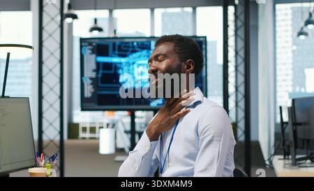 System administrator in tech startup office using PC, troubleshooting hardware and software issues. IT professional at work monitoring and optimizing performance using computer, camera A Stock Photo