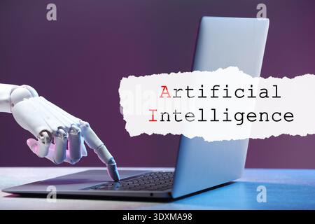 Robot using laptop. Text Artificial Intelligence on torn paper Stock Photo