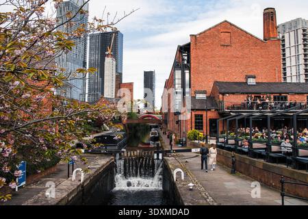 Castlefield canal basin in Manchester with narrowboats, historic brick warehouses and modern skyline, popular urban district in England. Stock Photo