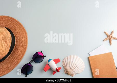 Strow hat, sunglasses, toy airplane, notepad, starfish and seashell on light blue background. Travel concept. Top view, flat lay, copy space Stock Photo