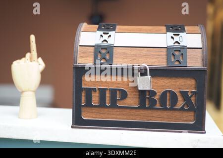 Tip box and wooden hand gesture in a cafe setting Stock Photo