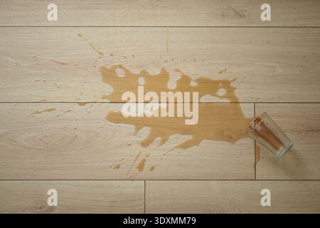 Coffee spills on wooden floor near glass Stock Photo