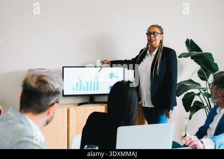 Diverse business people discuss financial project inside office - Group of colleagues during meeting - Focus on african senior woman face Stock Photo