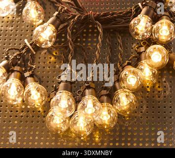 Decorative string lights featuring glowing bulbs are arranged on a textured surface, highlighting warm illumination and intricate wiring details Stock Photo
