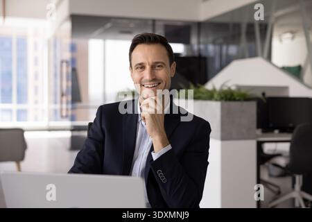Portrait Hispanic male executive working on laptop at office desk Stock Photo
