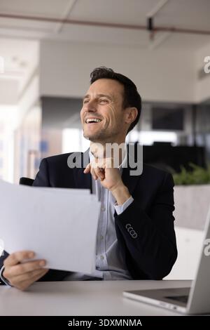 Smiling Hispanic businessman reviewing legal paper documents at workplace desk Stock Photo