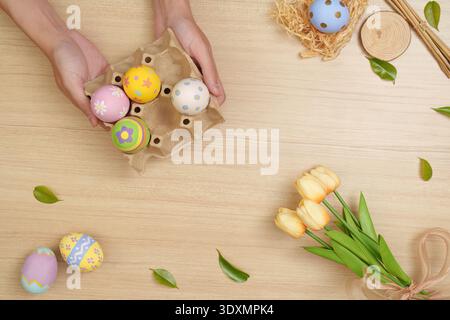 Easter Fun. Hands holding decorated eggs from a carton for festive celebration. Stock Photo