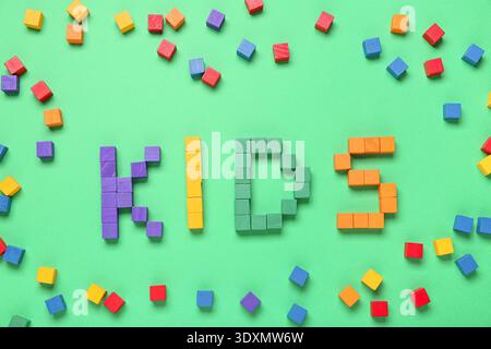 Word KIDS made of colorful cubes on green background Stock Photo