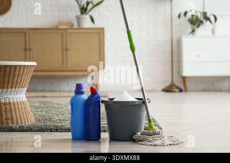 Mop with bucket of water and detergents on floor in living room Stock Photo
