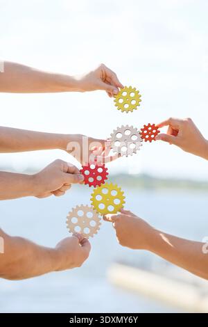 Many hands with gears outdoors Stock Photo