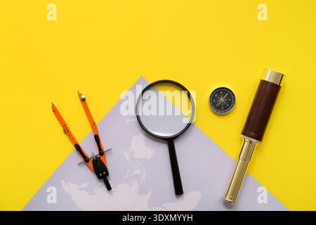 Composition with modern compass, spyglass, world map and divider on yellow background Stock Photo