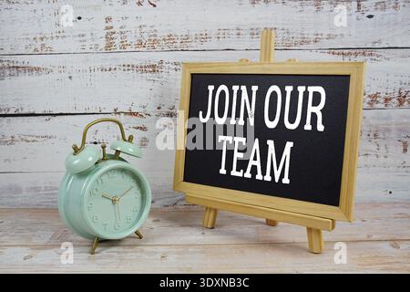 Join Our Team text written on blackboard with alarm clock on wooden background Stock Photo