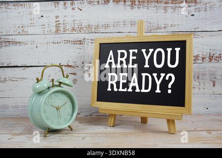 Are You Ready? text written on blackboard with alarm clock on wooden background Stock Photo