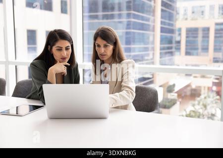 Two professional women analyzing important information on laptop Stock Photo