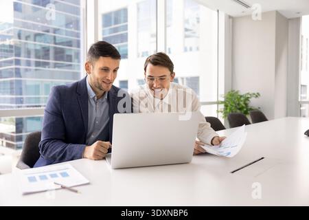 Two smiling team members sitting at conference table with laptop Stock Photo