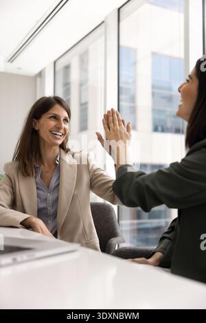 Vertical image of two professional businesswomen exchanging high-five Stock Photo