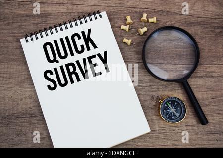 Quick Survey text written on notepad with compass and magnifying glass flat lay on wooden background Stock Photo