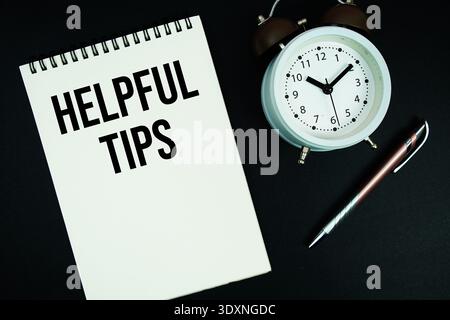 Helpful Tips text written on notepad with pen and alarm clock Stock Photo