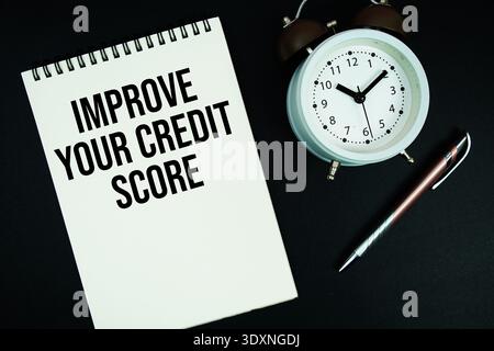 Improve Your Credit Score text written on notepad with pen and alarm clock Stock Photo