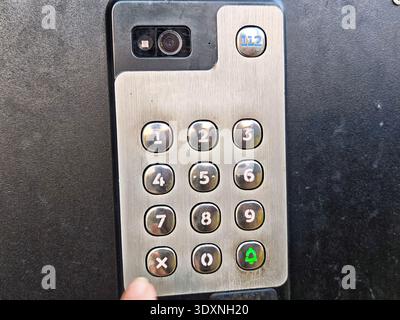 Close view of a hand entering access code on intercom keypad at an entrance for building security and door entry. Stock Photo