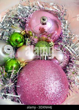 Colorful Christmas ornaments with pink and green baubles and silver tinsel, festive holiday decoration background with shiny textures and soft light. Stock Photo