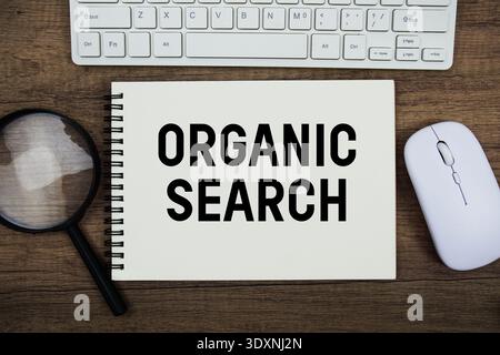 Organic Search text written on notepad with keyboard, optical mouse and magnifying glass on wooden background Stock Photo