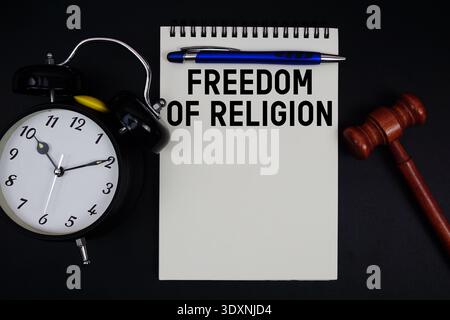 Freedom of Religion text written on notepad with gavel and alarm clock on black background Stock Photo