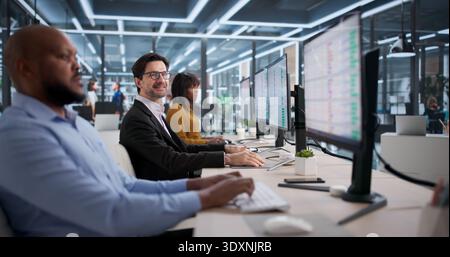 Diverse Team Of Accountants And Coders Smiling While Using Spreadsheets On Computers. Stock Photo