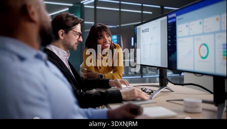 Diverse Team Of Office Workers Analyzing Billing Spreadsheets On Computers. Several People, Including A Manager Stock Photo
