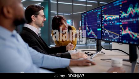 Young Professional Woman And Man Working At Computer, Analyzing Stock Market Data. The Trader Studies Financial Graphs Stock Photo