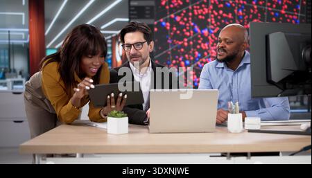 Diverse Team Of Professionals Using Laptops And Tablets For Data Analysis. People In An Office Working Together Stock Photo