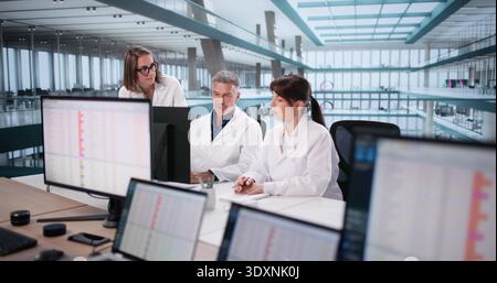 Medical Team Analyzing Billing Codes On Computer In Hospital Setting. Stock Photo