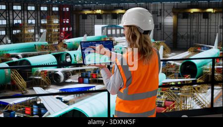 Aerospace Engineer Using SCADA Software In Factory Checks Airplane Panels. Stock Photo